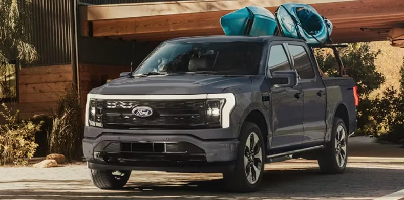 A grey 2026 Ford F-150 parked in a driveway with 2 Kayaks on top.