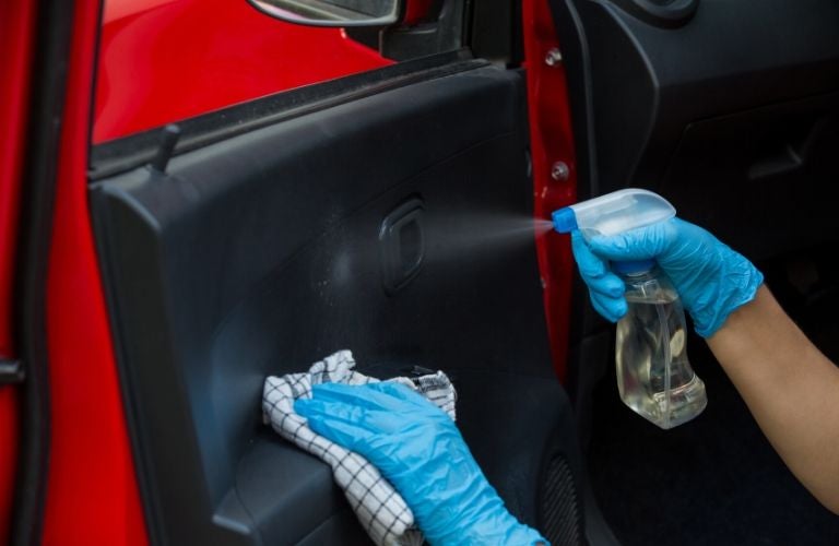 gloved hands cleaning interior of car