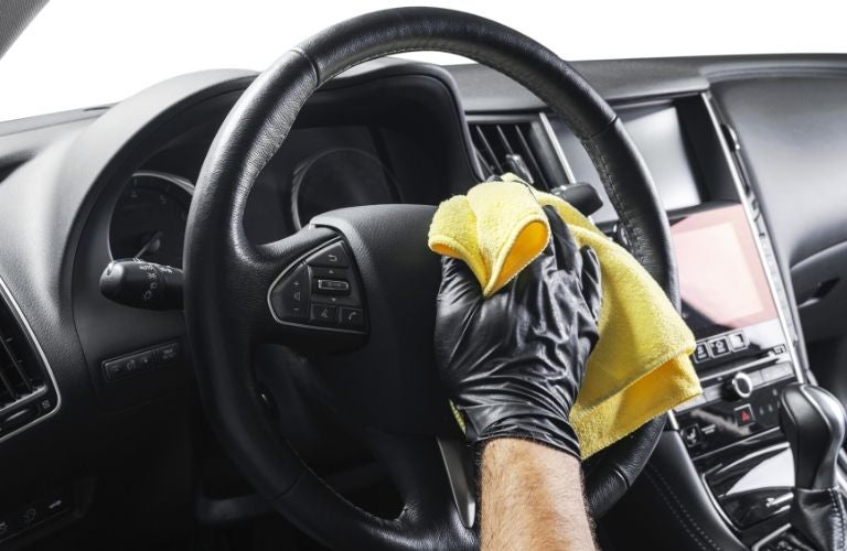 gloved hands wiping down steering wheel in a car
