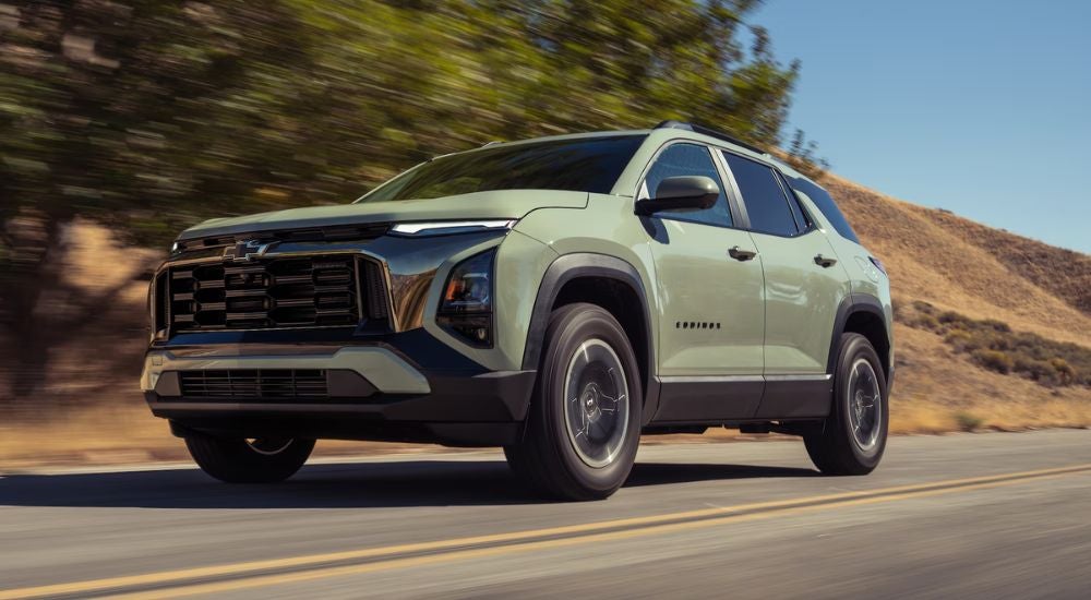 Green 2026 Chevy Equinox driving on a paved road.