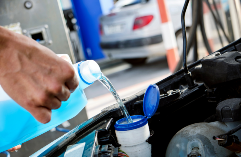 A mechanic adding coolant to a vehicle 
