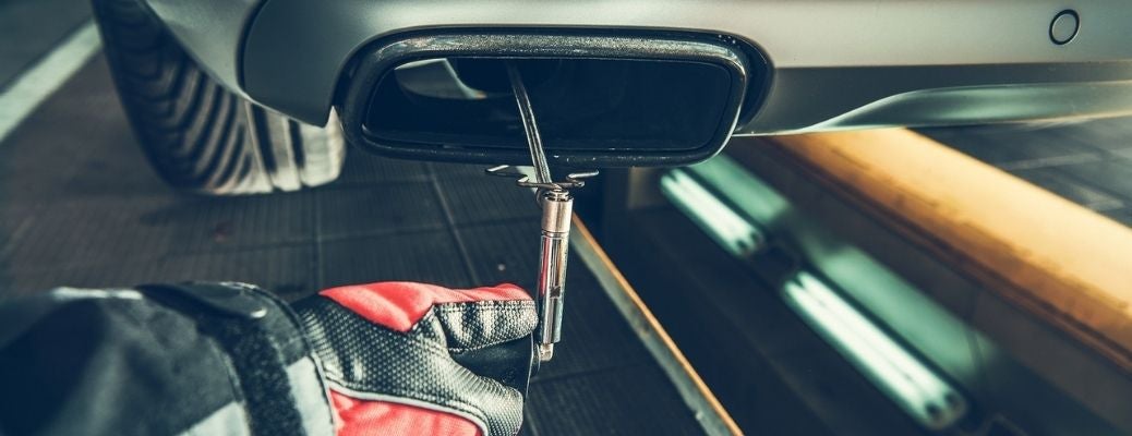A mechanic checking an exhaust for repair