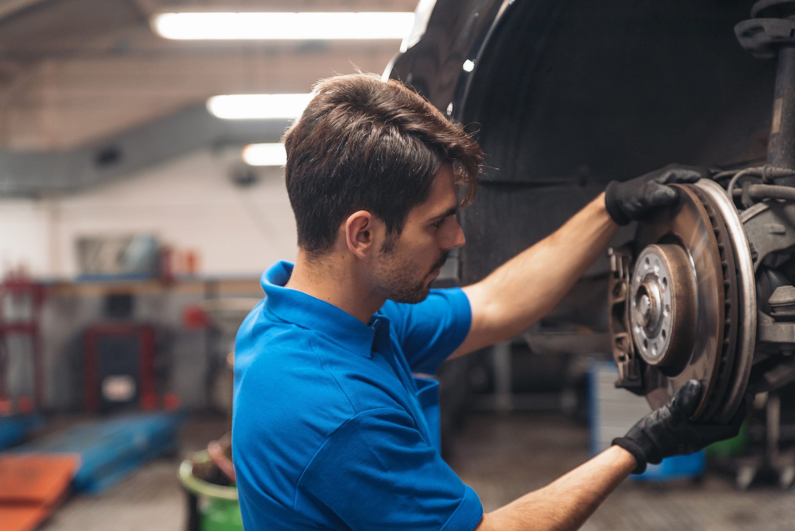A mechanic working on a car's brake system in a workshop