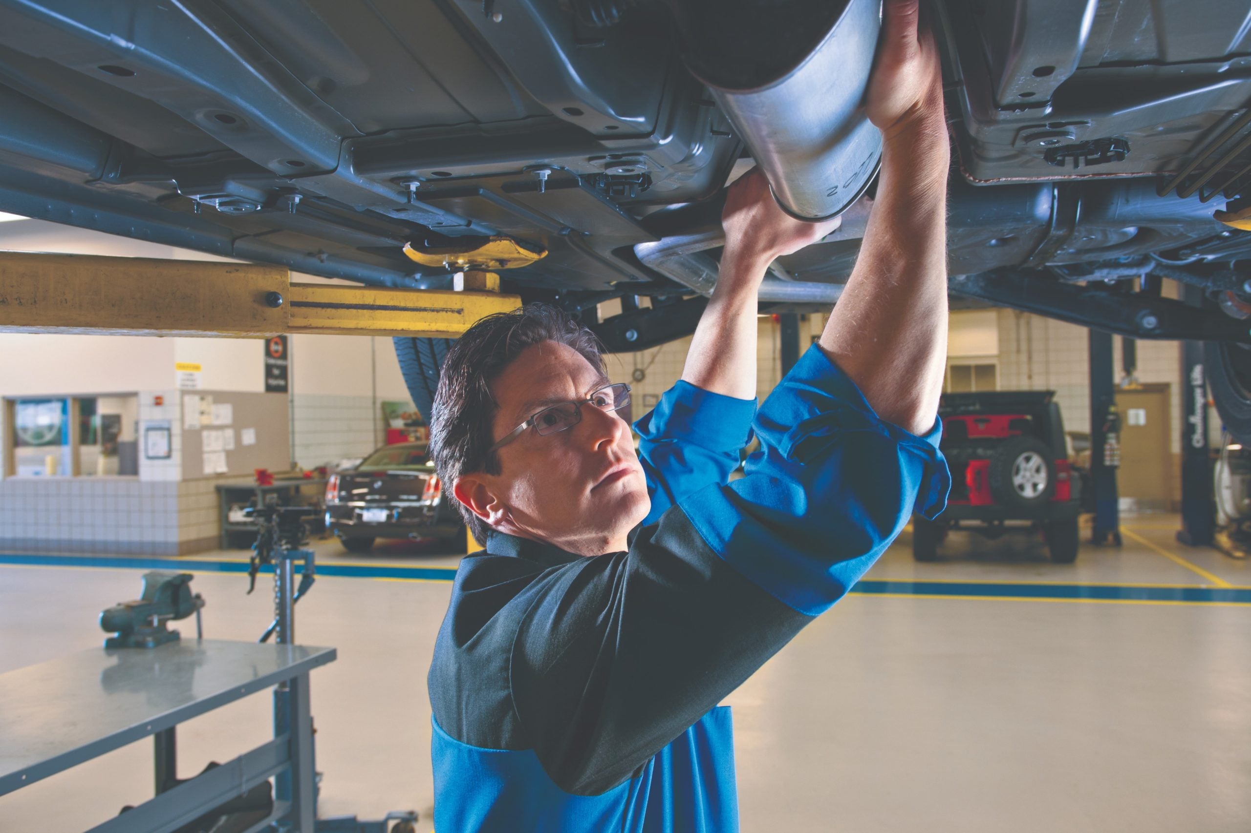 A mechanic inspecting and working on a car exhaust system