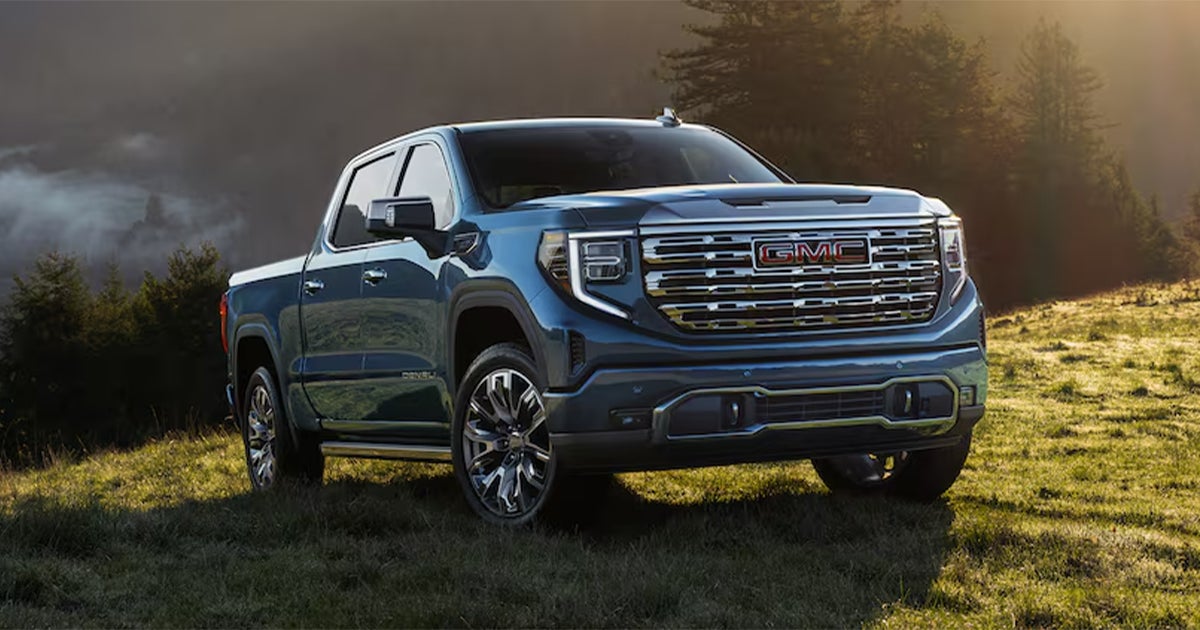 A blue GMC Sierra 1500 pickup truck parked in an open field.