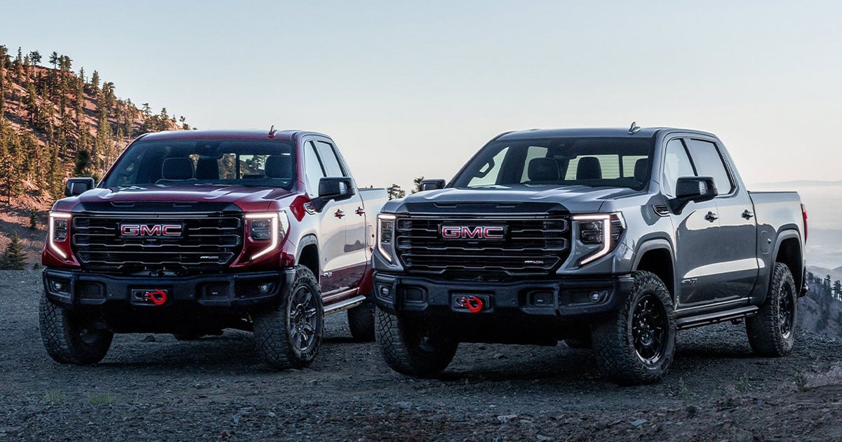 Two GMC Sierra HD pickup trucks parked beside each other on a mountain.