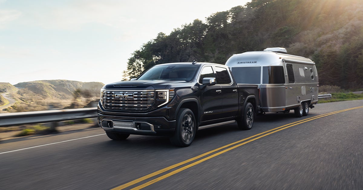 A GMC Sierra 1500 towing a trailer behind it on the road