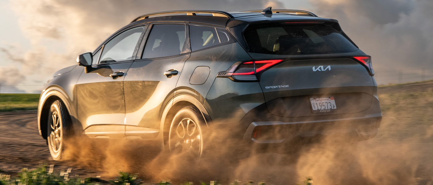 A Kia vehicle driving in some dust