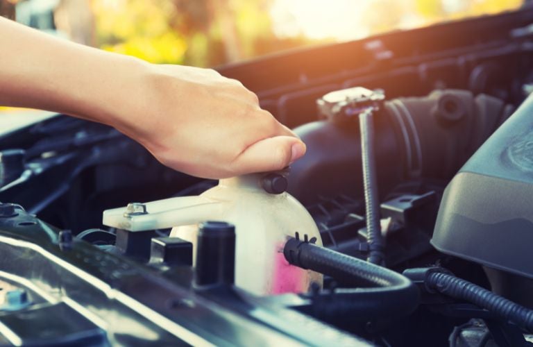 A hand checking the engine's coolant