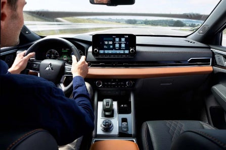 Man Driving 2024 Mitsubishi Outlander Plug-In Hybrid with Black and Tan Interior