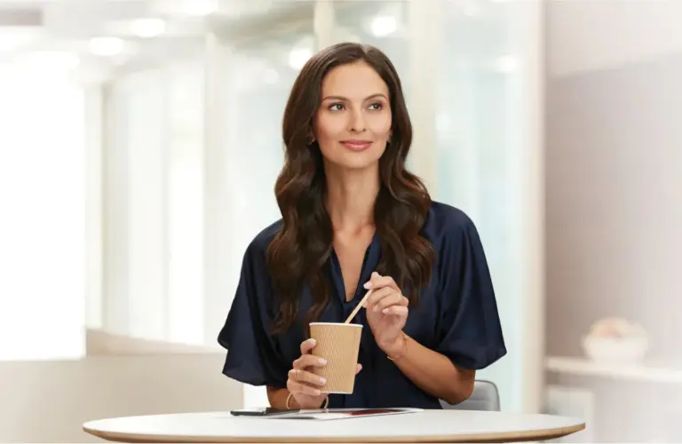Woman stirring coffee in a service waiting room at an INFINTI dealership