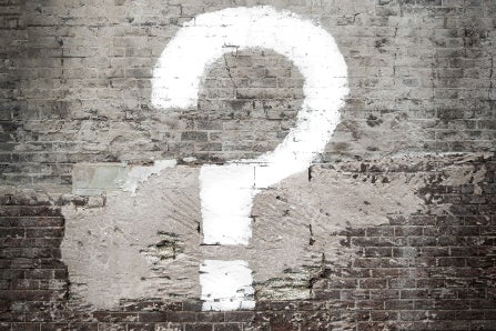 White question mark painted on gray brick wall