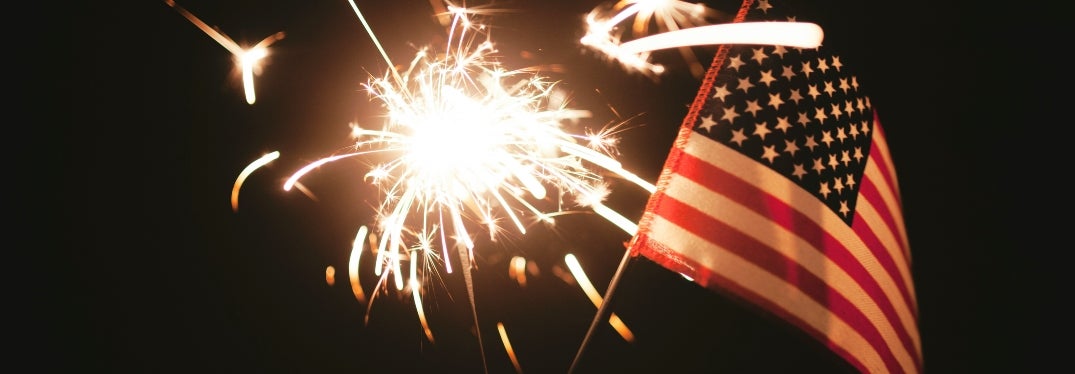 Small United States flag in front of fireworks at night