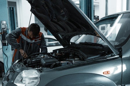 mechanic working on car with hood up