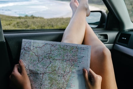 Woman Looking at Map with Feet out Car Window