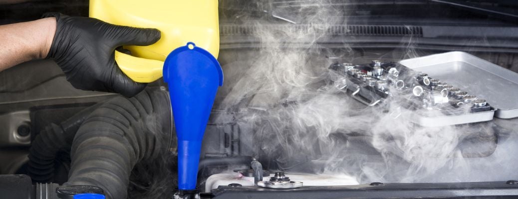 Technician pouring coolant in an overheated engine