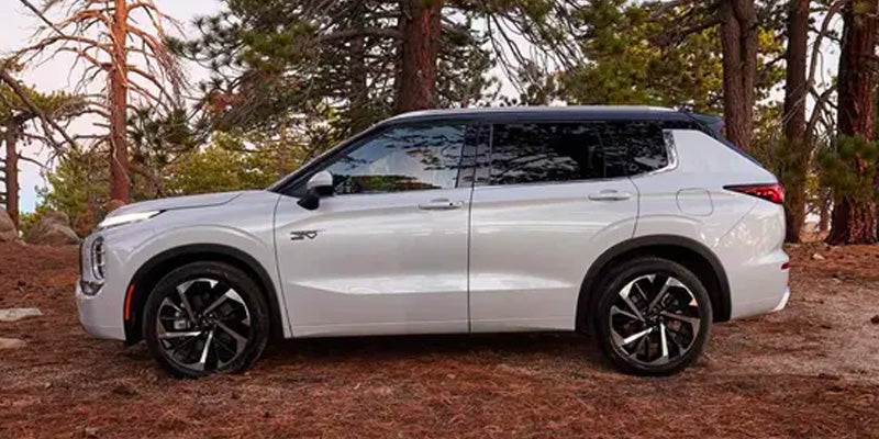 White 2025 Mitsubishi Outlander-PHEV facing left in the forest near Morgantown, WV