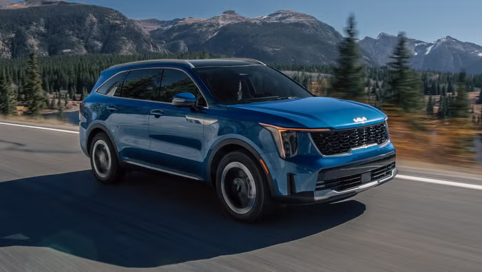 Blue Kia Sorento SUV driving through a mountain road