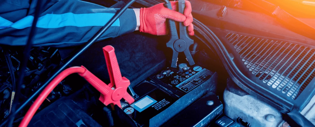Kia technician jumpstarting a Kia battery at a service center