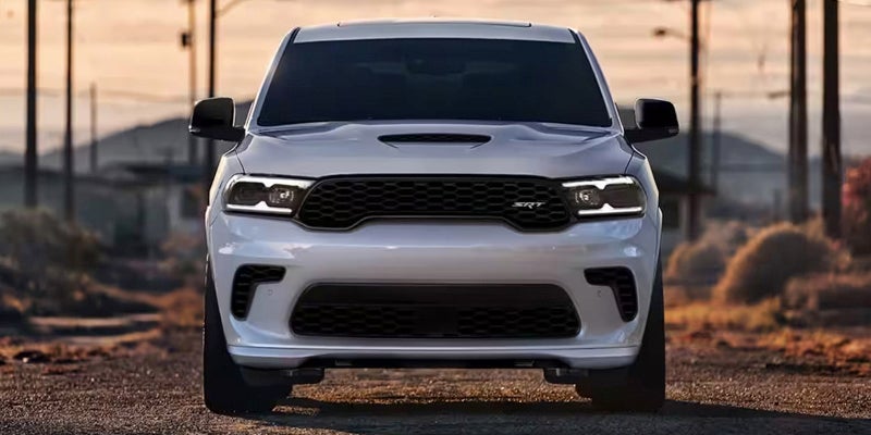 A white 2024 Dodge Durango driving straight towards the camera on a desert road. 