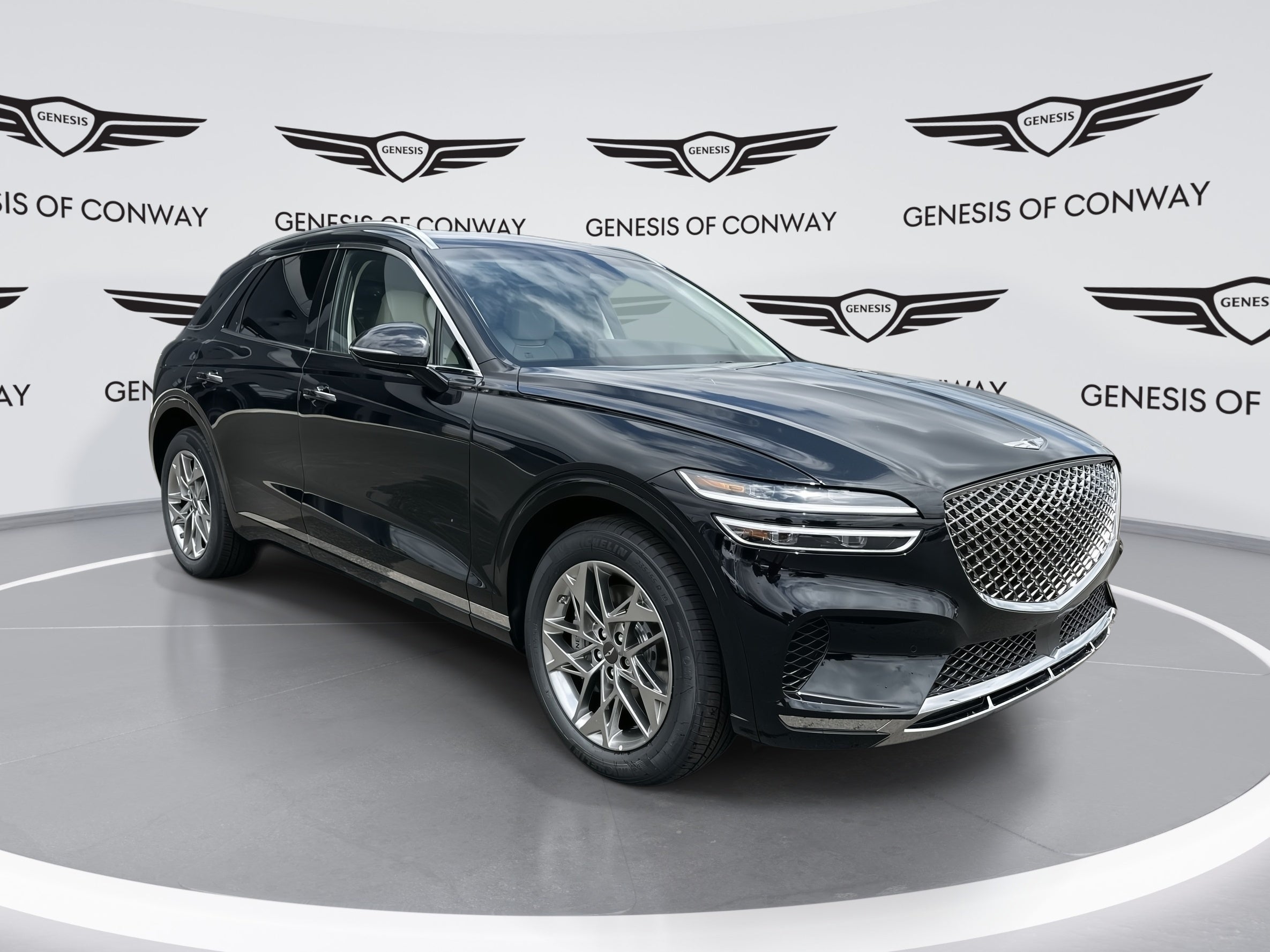 Front angle view of a black Genesis GV70 SUV in the Genesis of Conway showroom, winner of a 2025 Car and Driver Editors’ Choice Award
