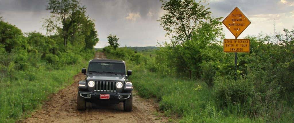 Jeep Wrangler on a dirt road with a warning sign
