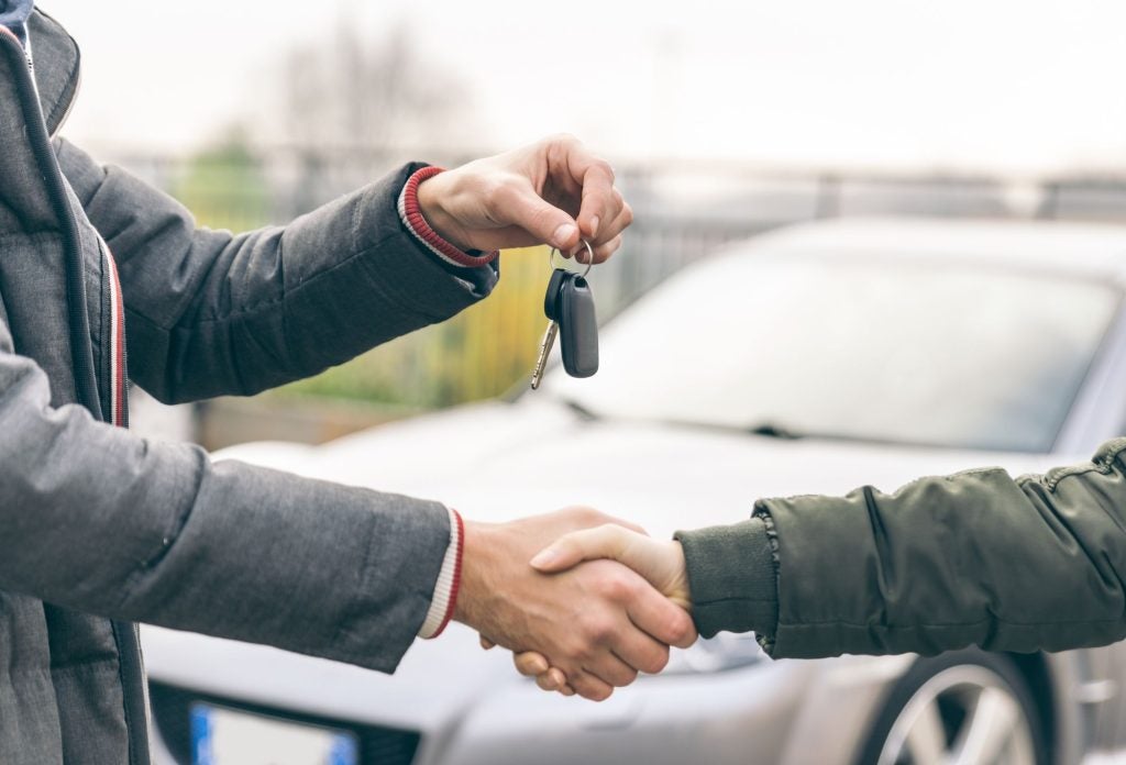 Salesperson shaking hands with a customer and handing them the keys to their vehicle after getting a Trade-in Value.