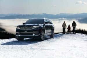 Black Grand Cherokee L in the snow with a family skiing
