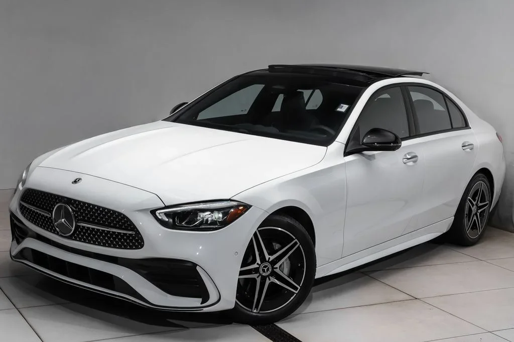 White Mercedes-Benz sedan with black accents in a showroom.