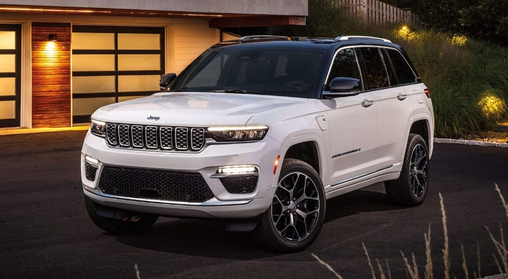 White 2024 Jeep Grand Cherokee 4XE parked in a driveway.