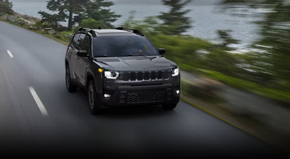 A black 2026 Jeep Cherokee driving on a highway.