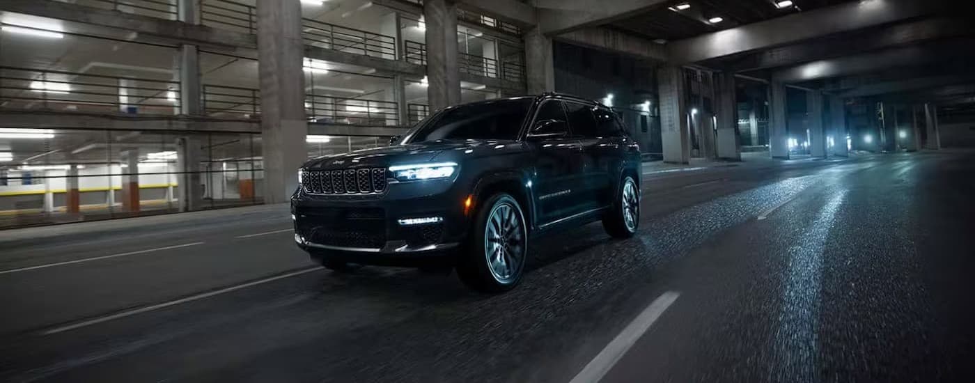 A black 2025 Jeep Grand Cherokee driving at night.
