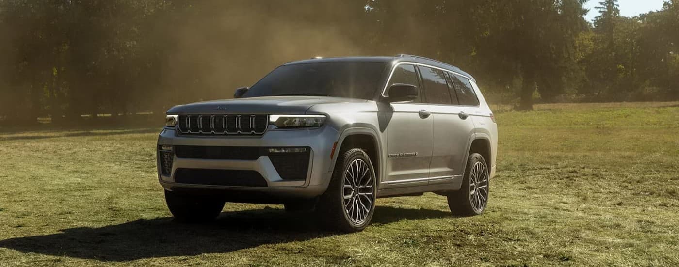 A silver 2026 Jeep Grand Cherokee parked on grass.