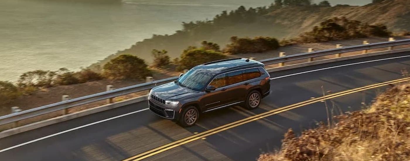 A silver 2026 Jeep Grand Cherokee driving on a highway.