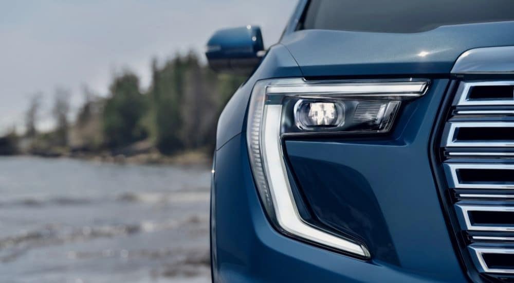 A close up shows the passenger side headlight on a blue 2024 GMC Acadia Denali.