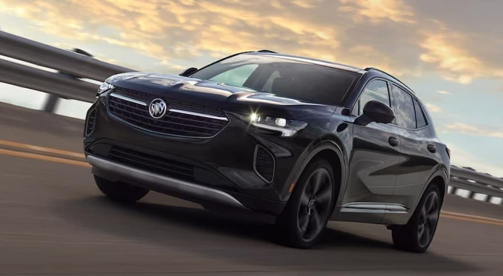 A black 2024 Buick Envision driving on a bridge from a dealer with a Buick Envision for sale.