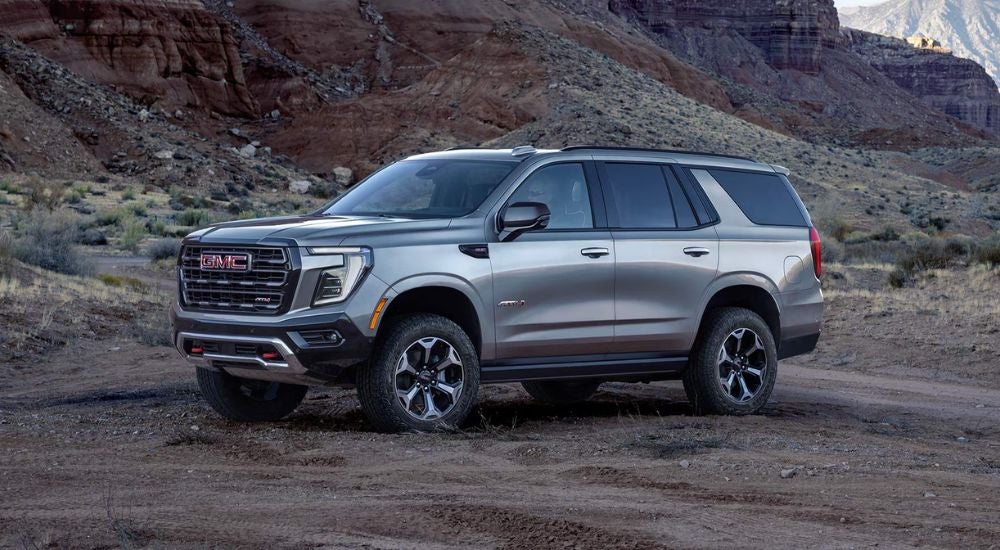 Grey 2027 GMC Yukon AT4 off-road in the desert.
