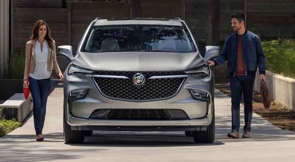 A couple is shown approaching a silver 2024 Buick Enclave.