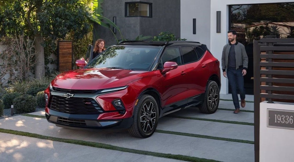 A couple walking towards a red 2024 Chevy Blazer RS.