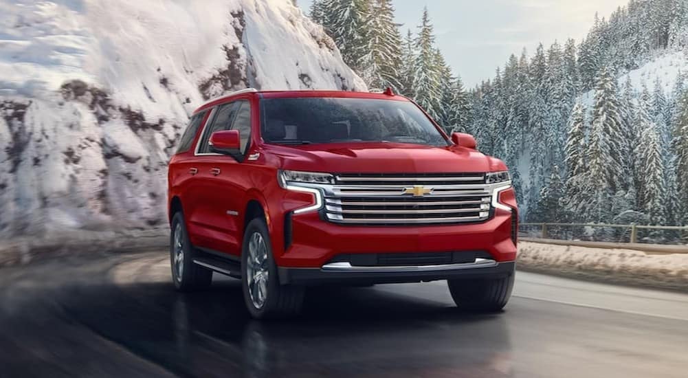 A red 2024 Chevy Suburban is shown driving to visit a Chevy dealer near Ann Arbor.