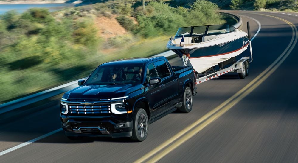 Black 2027 Chevy Silverado 1500 High Country towing a boat.