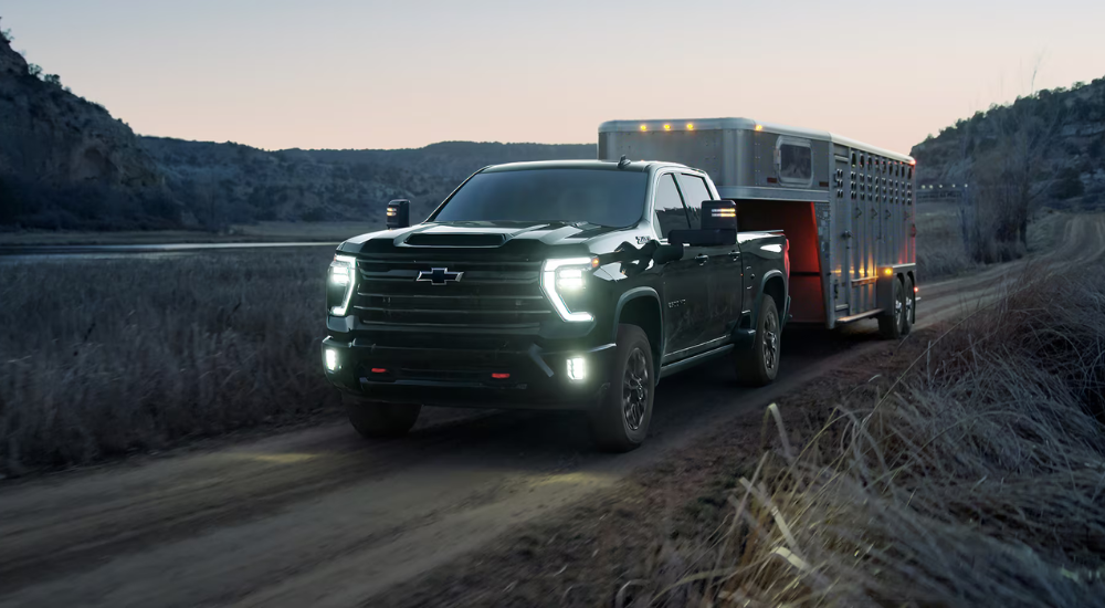 Black 2026 Chevy Silverado 3500 HD towing a horse trailer.