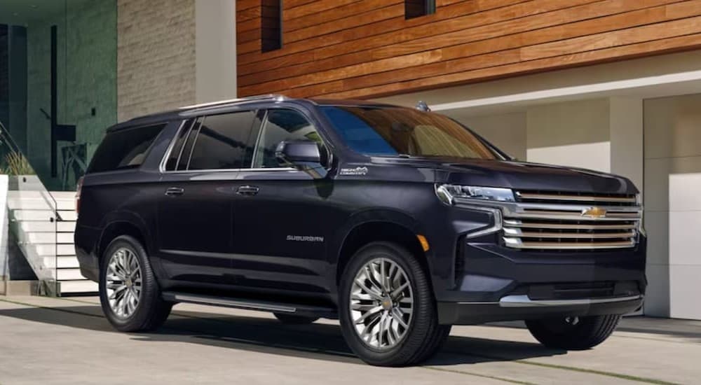 A blue 2023 Chevy Suburban parked near a used Chevy for sale.