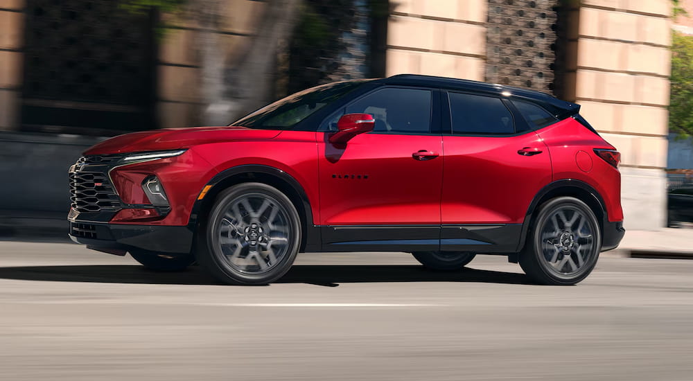 A red 2025 Chevy Blazer driving through a city from a Chevy dealer near Whitmore Lake.