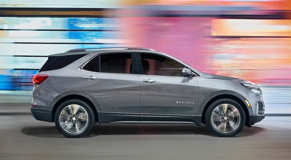 A silver 2023 Chevy Equinox driving in a city.