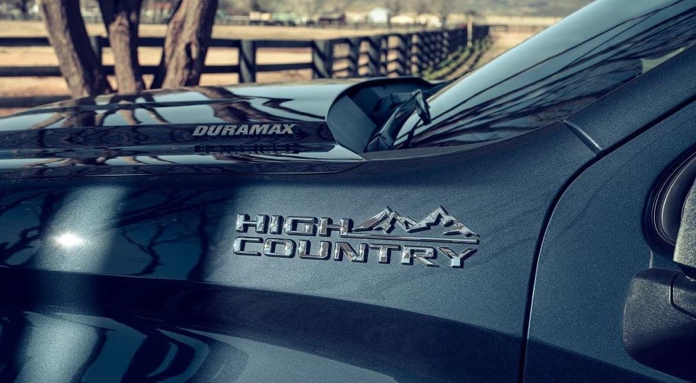 A close-up on the badge of a black 2024 Chevy Silverado 1500 High Country.