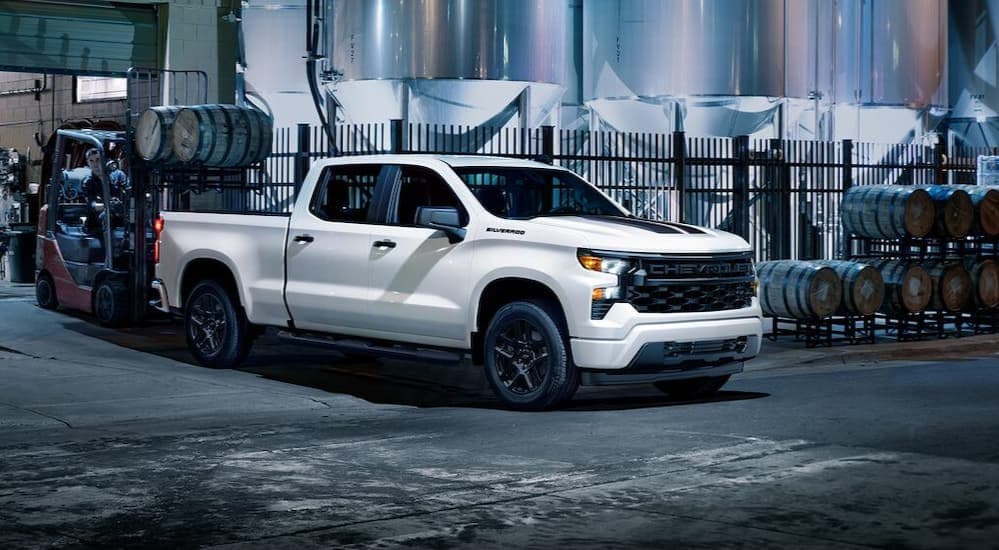 A white 2024 Chevy Silverado 1500 parked near many barrels.