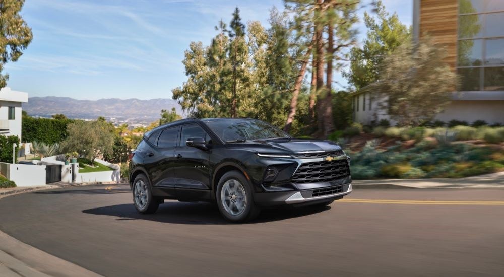 A black 2024 Chevy Blazer 3LT driving through a suburban area.