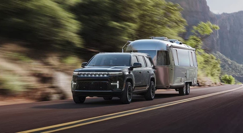 A black 2027 Jeep Grand Wagoneer towing a trailer.