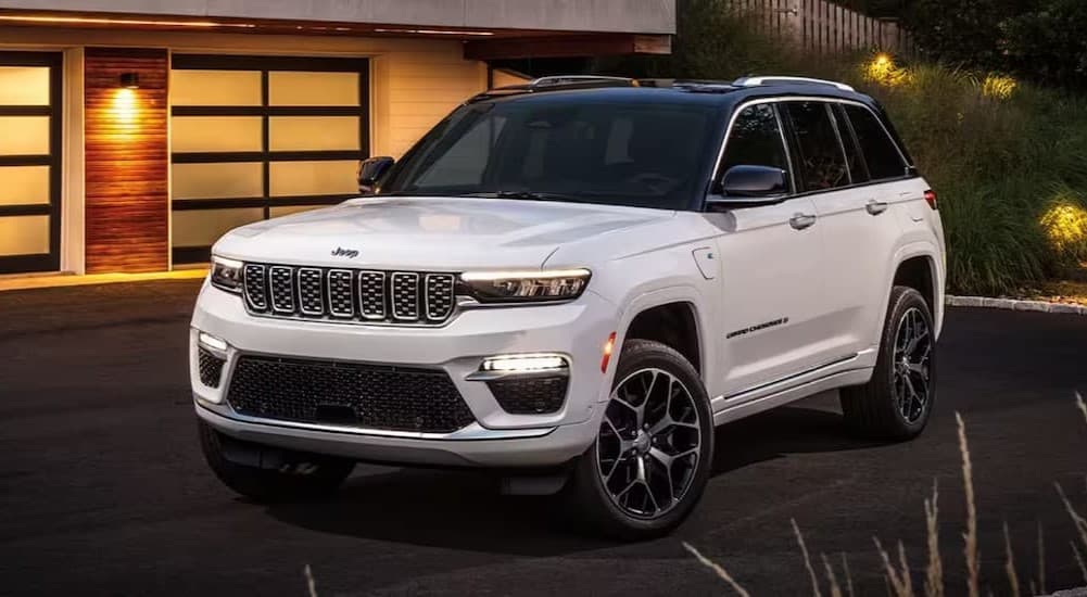 A white 2024 Jeep Grand Cherokee parked near a house.